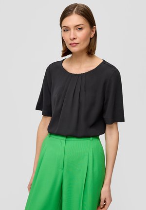 Zwarte blouse met korte mouwen en geplooide details, met een ronde halslijn, gecombineerd met hooggetailleerde, felgroene wijde broek.