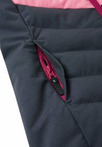 Dettaglio della giacca imbottita con un esterno grigio scuro, foderato di rosa, e una cerniera laterale con un tirante nero e cuciture a contrasto.