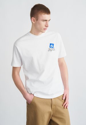 Hvit bomulls-T-skjorte med blått stempelmotiv på venstre bryst med teksten "the new originals", kombinert med khakifargede bukser.