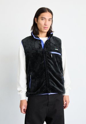 Black fleece vest with a textured surface, purple accents, stand-up collar, two zip pockets, and a front zip closure.