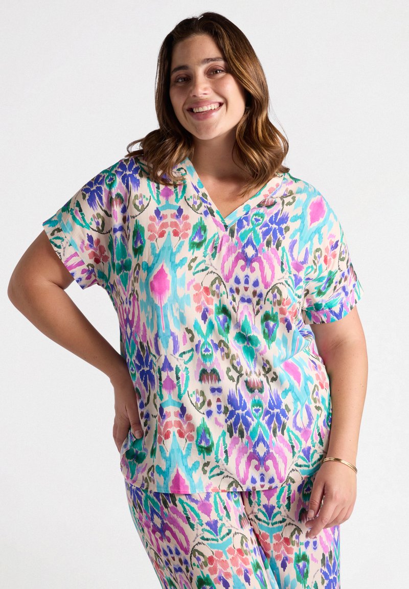 Camisa colorida de manga corta con cuello en V. Presenta un vibrante diseño floral y abstracto en rosa, verde, azul y púrpura sobre un fondo claro.