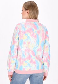 Felpa colorata con motivo tie-dye nei toni pastello di rosa, blu e giallo. Presenta una texture morbida, maniche lunghe e un orlo ribattuto rosa.