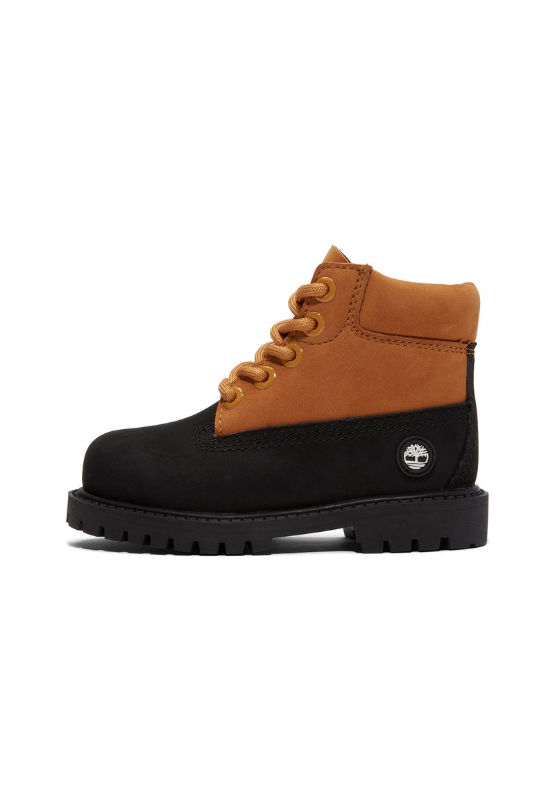 Botas de media altura en negro y marrón, hechas de ante y cuero, con ojales dorados, cordones, una suela de goma y un logo en el lateral.
