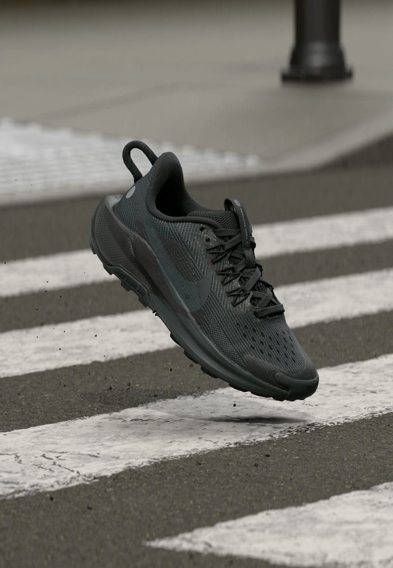 Chaussure de sport noire avec une tige en maille respirante, surface texturée et semelle en caoutchouc. Les lacets sont bien serrés et disposent d'une languette.