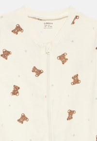 Krēma krāsas bērnu pidžama ar brūnu lāču attēlu un mazām zvaigznītēm un mēness rakstiem, ar rāvējslēdzēja aizdari, izmērs 6-9 mēneši.