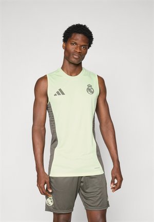 Toppe sportivo verde chiaro e pantaloni corti grigi scuri, entrambi con il logo del Real Madrid e tre strisce nere sulla spalla sinistra della maglia.