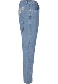 Jean en denim bleu clair avec une poche latérale, des passants de ceinture et un texte beige sur la partie supérieure de la cuisse.