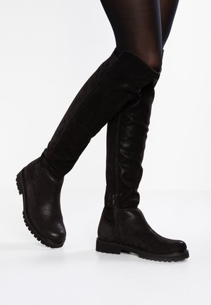 Bottes noires au-dessus du genou avec un mélange de daim lisse et texturé. Elles présentent une semelle épaisse basse et une fermeture éclair latérale pour un enfilage facile.