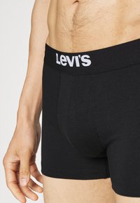 Mustat puuvillabokserit, joissa on valkoisella merkattu joustava vyötärönauha "Levi's", ja jotka ovat muotoiltu ja sileäpintaisia.