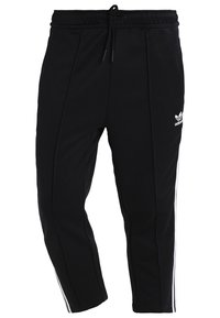 Černé sportovní kalhoty s bílými bočními pruhy, elastickým pasem a šňůrkou na stažení. Vyrobené z měkké látky s designem zužujících se nohavic.