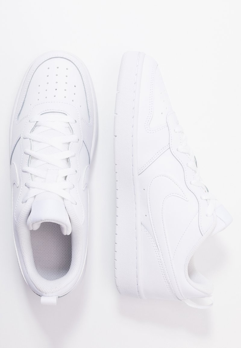 Paire de baskets basses blanches, l'une montrant une vue de dessus avec lacets, l'autre montrant un profil latéral avec logo swoosh sur fond blanc uni.
