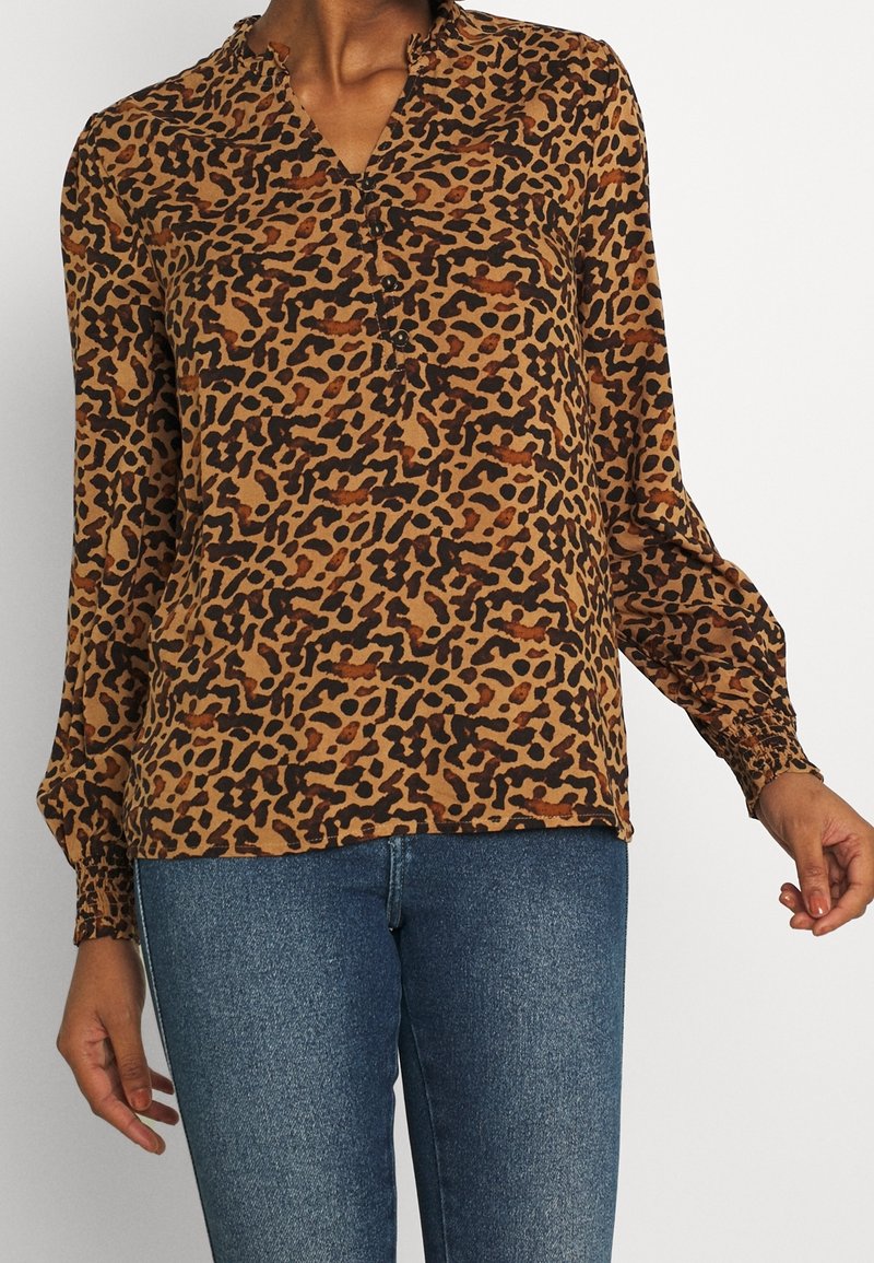 Blusa a fantasia di leopardato marrone con colletto e patta dei bottoni, presenta maniche lunghe con polsini elasticizzati e una vestibilità rilassata.