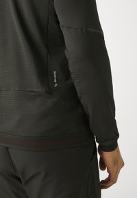 Sort langærmet top lavet af struktureret materiale med en tætsiddende pasform; har et POLARLITE-logo på siden og en mesh talje.