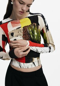 Pullover a maglia multicolore con motivi audaci in rosso, giallo, crema e verde, con polsini a coste e design aderente.