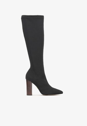 Schwarze knöchelhohe Stiefel aus geripptem Stoff mit spitzer Zehe und einem klobigen Holzabsatz. Glatte Textur mit minimalen Details.