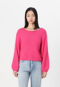 Bright pink knitted sweater with a wide neckline and long, balloon-style sleeves, finished with a ribbed hem. Paired with light blue jeans.