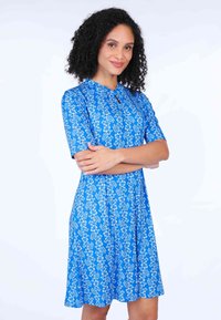 Blaues Blumenkleid mit kurzen Ärmeln, einem Schlüsselloch-Ausschnitt und einem ausgestellten Rock. Bietet weiße Blumenmuster auf einem einfarbigen blauen Hintergrund.