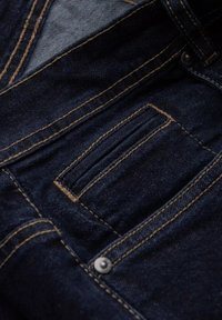 Jeans de mezclilla azul oscuro con costuras amarillas y un pequeño bolsillo frontal. La tela tiene una apariencia suave y ligeramente texturizada.