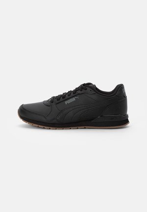 Sort Puma-brandet sneaker med snørebånd foran, tekstureret sål og syninger vist i sideprofil på lys baggrund.