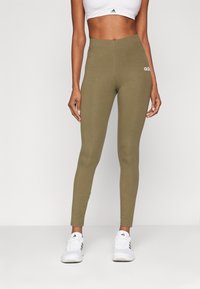 Olivgröna leggings med hög midja, tillverkade av stretchigt tyg och med en liten vit Adidas-logotyp på framsidan.
