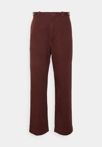 Bruna, rakbeniga byxor i strukturstickad bomull. Har dragkedja, bältesöglor och sidofickor. Inga synliga mönster eller detaljer.