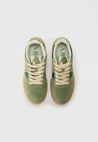 Grønne ruskinds sneakers med beige snørebånd, med et grønt sidepanel og en lys grøn mesh-tunge. Gummigummisål.
