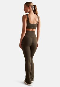 Soutien-gorge de sport côtelé vert olive et leggings taille haute, présentant une silhouette ajustée et un logo discret sur la ceinture.