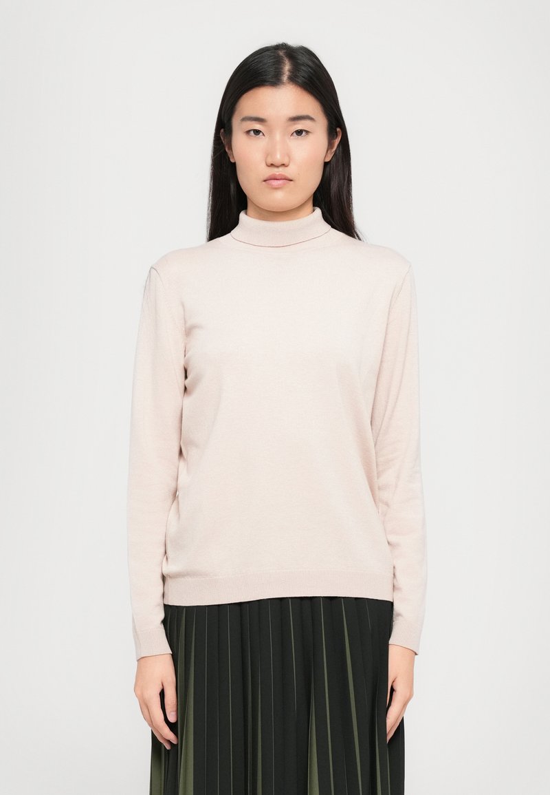 Light pink, long-sleeve turtleneck sweater made of a soft, smooth fabric with a fitted silhouette, paired with a dark pleated skirt.
