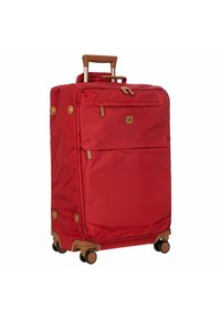 Valigia rossa con un esterno in tessuto resistente, una tasca frontale con zip, dettagli marroni, manico estraibile e quattro ruote per la mobilità.