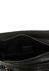 Interior de bolso de cuero negro que incluye un compartimento con cremallera, dientes de cremallera dorados y un suave revestimiento de tela negra con bolsillos adicionales.