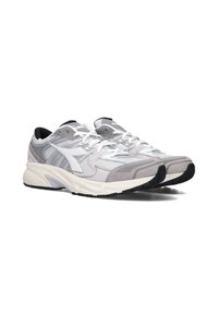 Scarpe da atletica leggere con una parte superiore in mesh grigia e bianca, dettagli texturizzati, colletto imbottito e suola in gomma nera. Presentano lacci bianchi.