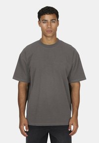 Szara, oversize t-shirt wykonana z miękkiej bawełny, z okrągłym dekoltem i krótkimi rękawami. Dyskretny akcent logo na klatce piersiowej.