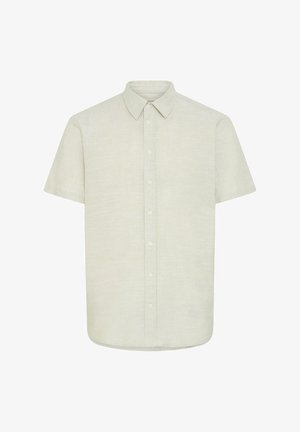 Chemise beige à manches courtes, boutonnée sur le devant, avec un col pointu, une patte de boutonnage frontale et un tissu subtilement texturé sur fond blanc.