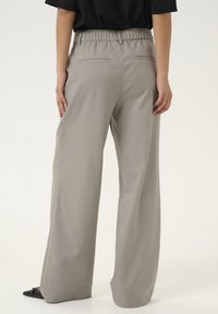 Pantalons larges gris avec une taille élastique, dotés de deux poches arrière. Tissu doux avec une finition mate.