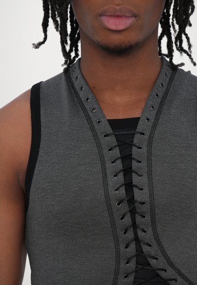Haut sans manches gris foncé avec un design à lacets à l'avant, présentant des œillets en métal et un revêtement noir contrastant le long des bords. Texture lisse.