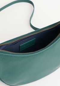 Borsa a tracolla in pelle color teal con zip dorata, interno in tessuto blu navy e una piccola tasca interna con etichetta del marchio cucita.
