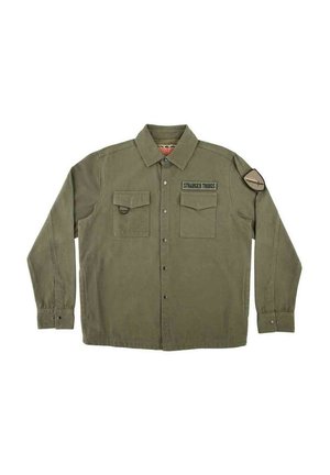 Camisa de color verde oliva con botones, dos bolsillos delanteros, parche de "Stranger Things" en el pecho y parche circular en la parte superior izquierda de la manga.