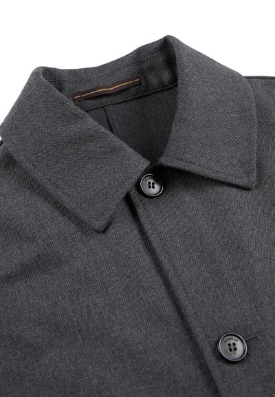 Cappotto grigio con colletto in tessuto texture, caratterizzato da un bottone nero e un sottile dettaglio marrone lungo il colletto.