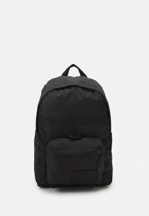 Czarny plecak Adidas z kieszenią na suwak z przodu, górnym uchwytem oraz wyściełanymi paskami na ramiona, pokazany na jednolitym białym tle.
