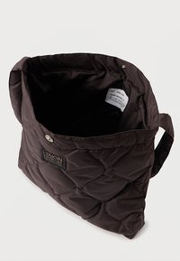 Καφέ με επένδυση τσάντα tote με μαλακή υφή, με άνοιγμα από πάνω και μια ετικέτα στο εσωτερικό. Διαθέτει λογότυπο και κλείσιμο με κουμπί.