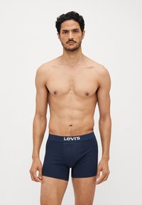 Mørkeblå boxershorts med myk, elastisk midje med Levi's-logo. Materialet virker glatt med en slim fit-design.