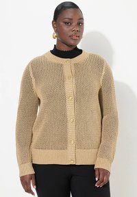 Cardigan a maglia beige con design a rete aperta, collo a giro, polsini a coste e bottoni sul davanti. Tessuto testurizzato, vestibilità rilassata.