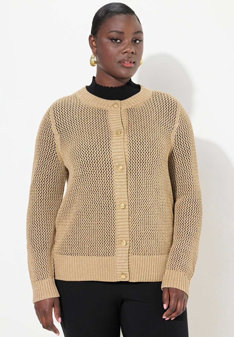Stickad cardigan i beige med öppen meshdesign, rundad halsringning, ribbade ärmslut och knappar framtill. Strukturerad tygkvalitet, avslappnad passform.