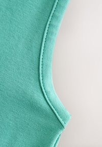 Tyrkysová bavlněná tílko s kulatým výstřihem, texturovanou tkaninou a čistým švem po obvodu.