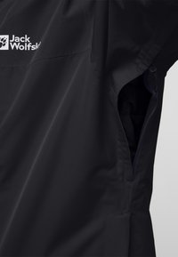 Veste noire imperméable avec une poche latérale zippée, design élégant et tissu texturé avec un logo en haut à gauche.