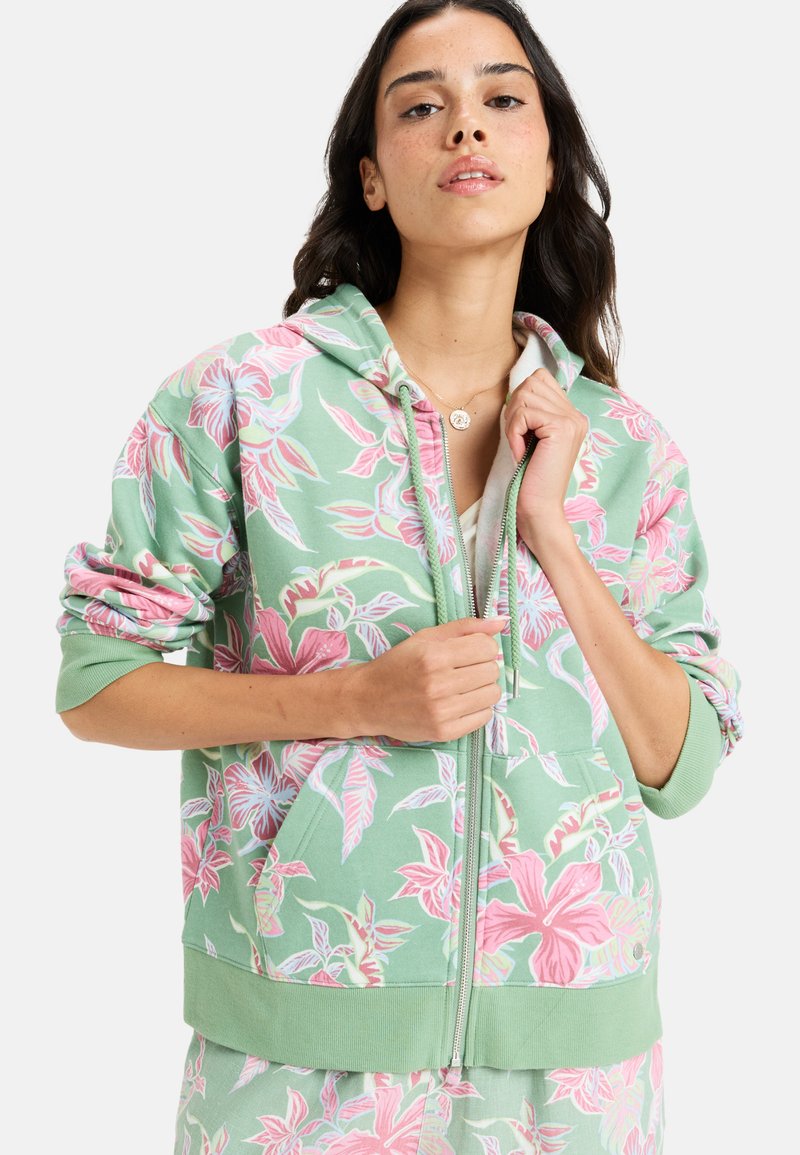 Felpa verde chiaro con zip e stampa floreale in rosa e bianco. Tessuto morbido con polsini e orlo a coste, e tasche frontali.