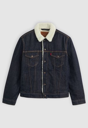 Dark denim jacket with a white faux shearling collar, two chest pockets, and gold stitching. Features button closure and a straight fit.