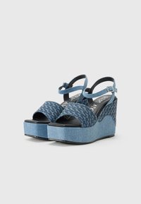 Denim plattform sandaler med ankelrem, med ett blått hundtandsmönster och texturerad kilklack. Svart fotbädd och justerbart spänne.