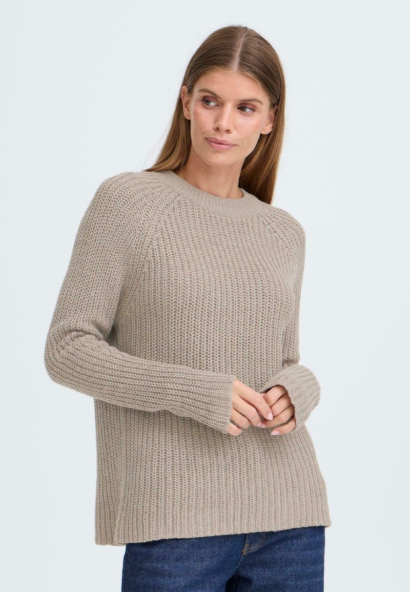 Beige strikket genser med rund hals, ribbede mansjetter og strukturert mønster. Den har en avslappet passform og mykt, tykt stoff.