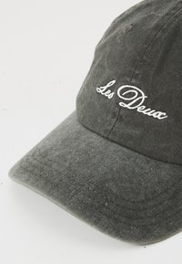 Gray cotton baseball cap with a curved brim. Features embroidered "Les Deux" logo in white. Textured fabric with visible stitching details.